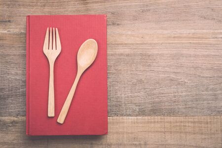 Top view spoon, fork and book on wooden plank background. Eating knowledge conceptの写真素材