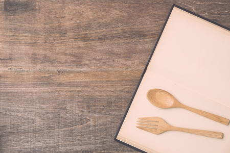 Top view spoon, fork and book on wooden plank background. Eating knowledge conceptの写真素材