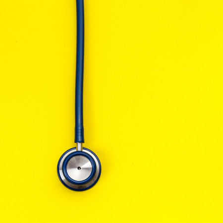 Top view blue stethoscope on yellow background. For check heart or health check up conceptの写真素材