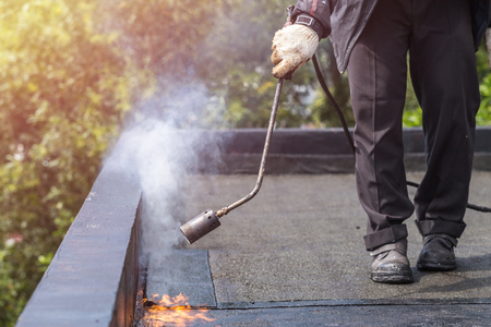 Asia worker installing tar foil on the rooftop of building. Waterproof system by gas and fire torchingの写真素材