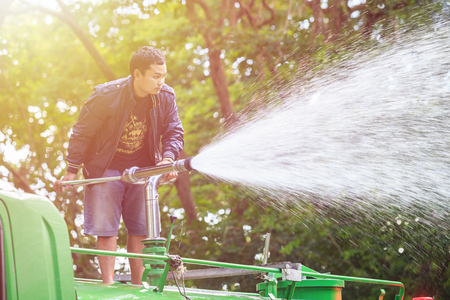 PHUKET, THAILAND - JUNE 20 : An unidentified people spraying water from the truck to landscape in the public park in Phuket on June 20, 2017.のeditorial素材