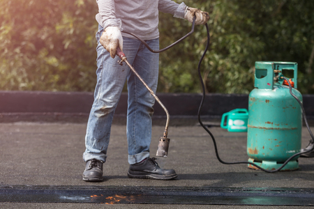 Asia worker installing tar foil on the rooftop of building. Waterproof system by gas and fire torchingの写真素材