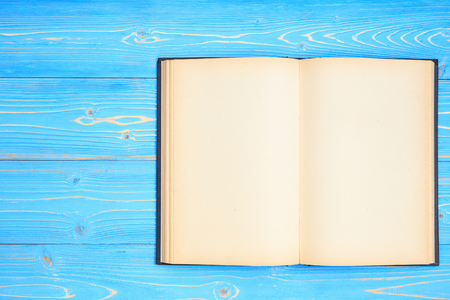 Top view old black open book on wooden plank background. Blank empty page for design