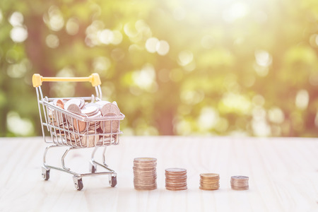 Close up hand putting coins in stack on wooden plank. savings concept.の写真素材