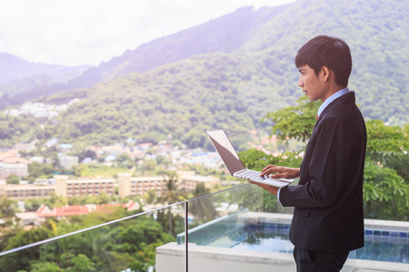 Portrait young asian businessman standing at the terrace looking to building and property. Used for real estate conceptの写真素材