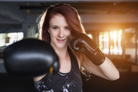 Beautiful young caucasian woman doing exercise with Thai boxing (Muay Thai) equipment in gym. Health and fitness concept.の写真素材