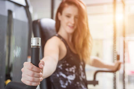 Beautiful young caucasian woman doing exercise with exercise equipment and machine in gym. Health...