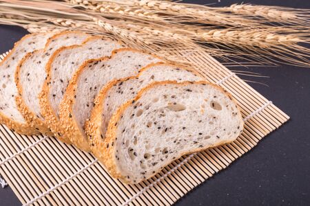 Slices of fresh white bread with sesame seeds on black stone table background. Top view and Studio shotの写真素材