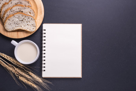 Slices of fresh white bread with sesame seeds and milk in white glass on black stone table background. Top view and Studio shotの写真素材