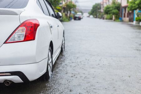 Car parking on the street of village while raining and show level of water flooding in Phuket, Thailandの写真素材