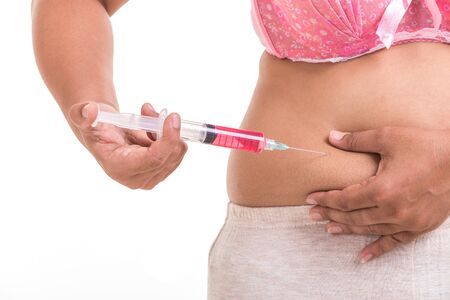 Fat woman holding syringe and inject red medicine to her belly isolated on white backgroundの写真素材
