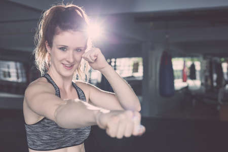 Beautiful young caucasian woman doing exercise with Thai boxing (Muay Thai) equipment in gym. Health and fitness concept.の写真素材