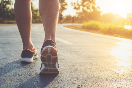 Man workout wellness concept : Close up runner feet with sneaker shoe running on road in the park....
