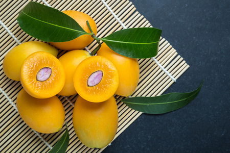 Close up fresh yellow marian plum fruit (Mayongchid in Thai name) on black stone. Top viewの写真素材
