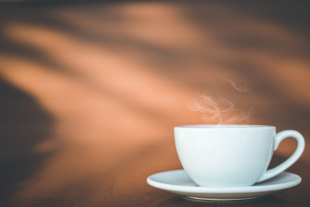 Close up white coffee cup on wooden table or counter in coffee shop and blur light bokeh background