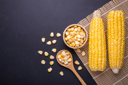 Fresh yellow sweet corn on the cob. Studio shot on black stone board background. For food concept. Top viewの写真素材