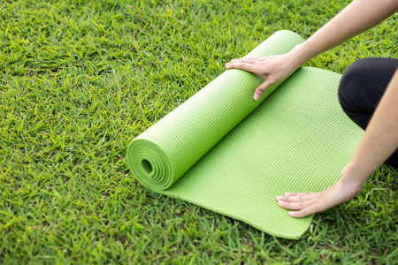Pretty asian holding green yoga mat and prepare for doing yoga exercises in the park. Used for relax and healthy conceptの写真素材