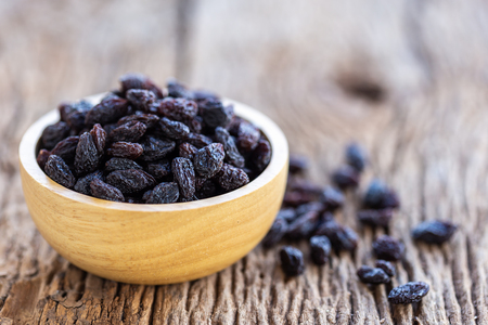 Close up raisins in bowl on wooden table background. Food conceptの写真素材