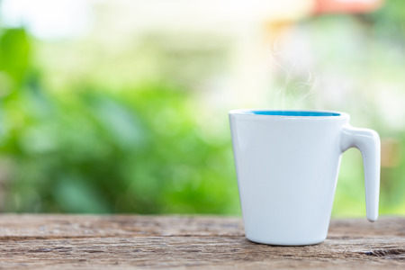 Close up white coffee cup on wooden table or counter in coffee shop and blur light bokeh backgroundの写真素材
