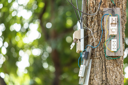 Dangerous electric cable and equipment set up on the tree in the parkの写真素材