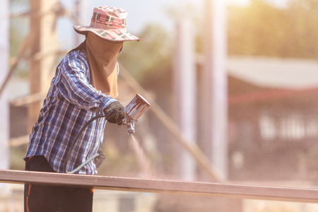 Construction worker spraying paint to steel pipe to prevent the rust on the surfaceの写真素材