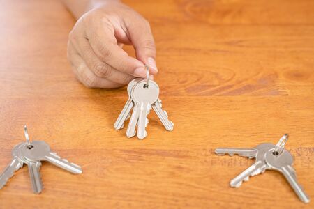Top view hand choosing set of home silver key on wooden table background