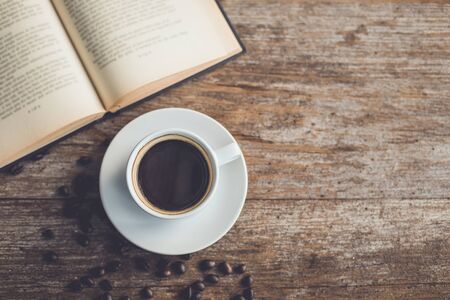 White ceramic coffee cup of black hot americano on wooden table or counter with book