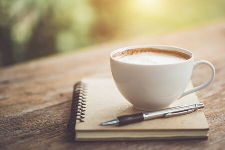 White ceramic coffee cup on wooden table or counter with morning nature light in garden conceptの写真素材