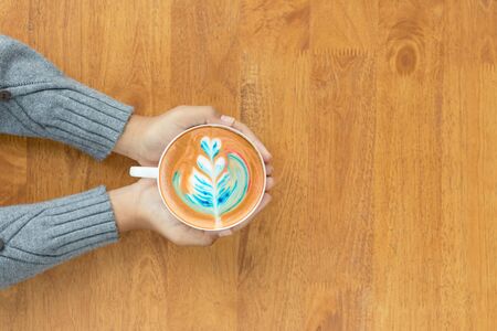 Two of people hand holding cup of hot Latte art coffee in cafe. Meetor socialize concept