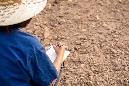 Asian student doing research or checking dry soil in empty land for planting. Environment Ecology and growing plant conceptの写真素材