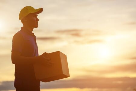 Delivery man holding brown parcel or cardboard boxes and delivery to customer at countryside and view of rice field. Can be delivery to anywhere conceptの写真素材