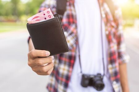 Hand of Asian tourist giving banknote and black wallet that he found in tourist attraction. Losing wallet conceptの写真素材