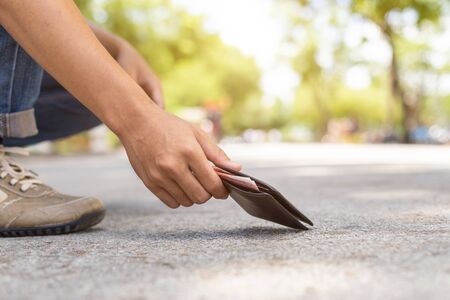 Asian man picking black wallet on the road in tourist attraction. Losing wallet concept