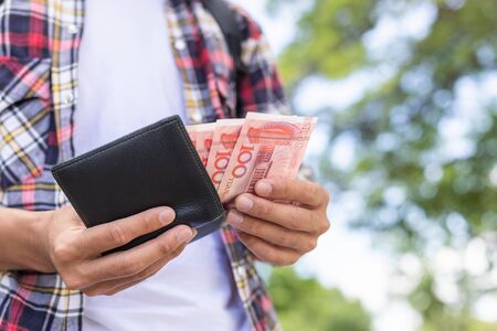 Asian tourist counting or checking banknote in black wallet that he found in tourist attractionの写真素材