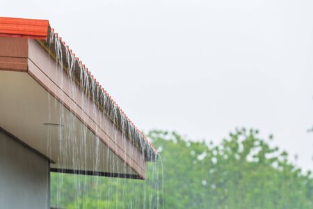 Rain flowing down from the roof house in rainy season