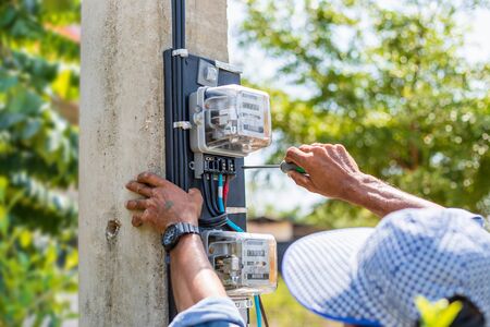 Technician installing electric meter on the pole to measurement watt in the house