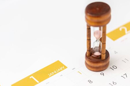 Close up vintage hourglass or sandglass on new year calendar for planning concept