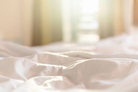 Close up white bedding sheets and pillow in hotel room at morning time with sunlight from windowsの写真素材