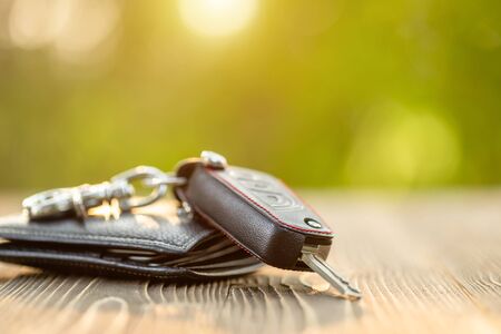 Close up new car keys with black leather wallet on wooden table. Car purchase or car rental conceptの写真素材