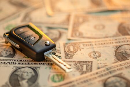 Close up new car keys with US dollar banknote on wooden table. Car purchase or car rental conceptの写真素材