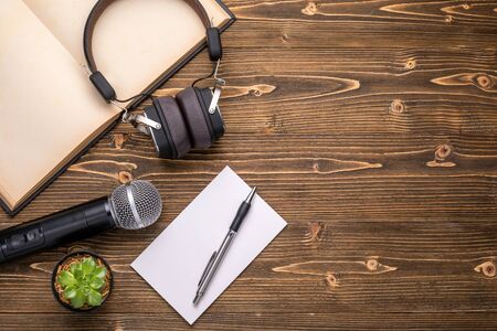 Top view microphone, headphone, book and paper note on brown wooden board. Learning about speaking conceptの写真素材