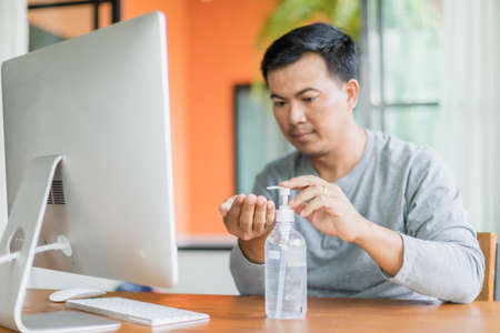 Asian man using hand sanitizer gel to clean his hand, Work from home and Healthy conceptの写真素材