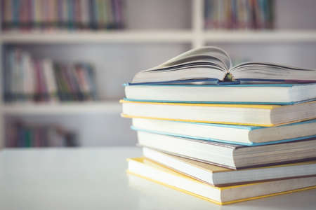 Close up book stack on the table in the library room and blurred space of bookshelf backgroundの写真素材