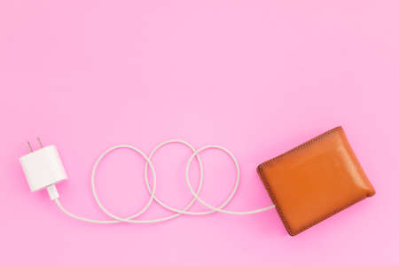 Charging the power to financial concept : Top view white charger cable connect to brown wallet on...