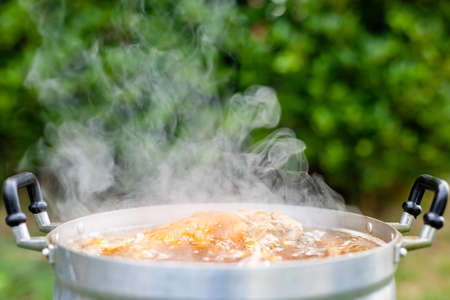 Close up stewed pork leg in silver pot on stove. Thai style food and outdoor cooking