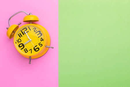 Top view old yellow alarm clock on bright color backgroundの写真素材