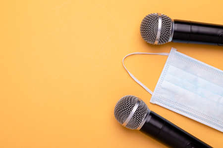 Still keep wearing mask while speak. Top view new preventive face mak and black wireless microphone on color background. Copy space for text or designの写真素材