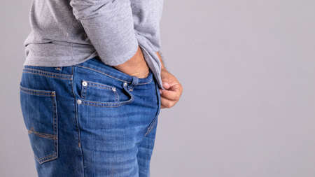 Itchy or Tinea Cruris concept. Man use hand scratching under his pant studio shot on grey backgroundの写真素材