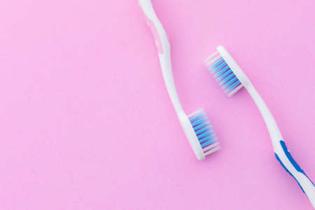 Top view new pink and blue toothbrush on pink background with copy space for text or design.