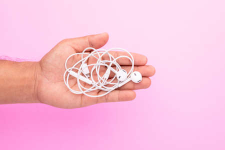 Top view white tangle earphone in hand on pink background. Copy space for text or designの写真素材